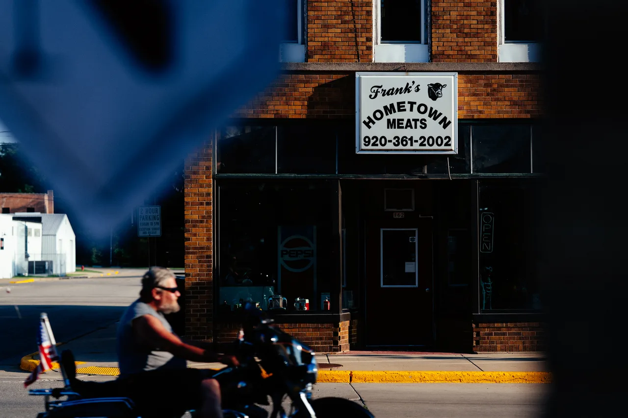 A motorcyclist passing Frank's Hometown Meats in Berlin, Wisconsin