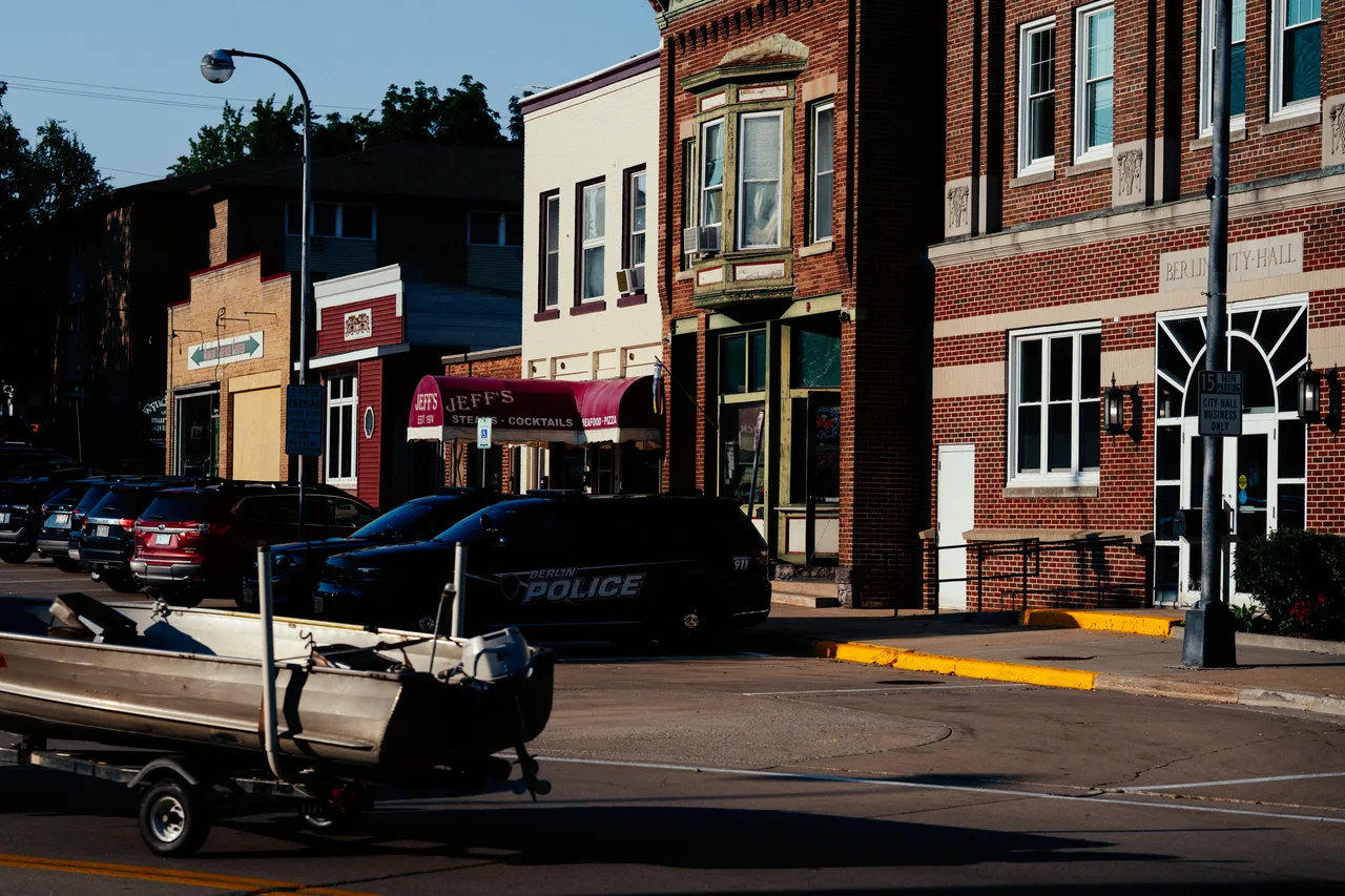 Downtown Berlin storefronts, city hall, a police car and a passing boat