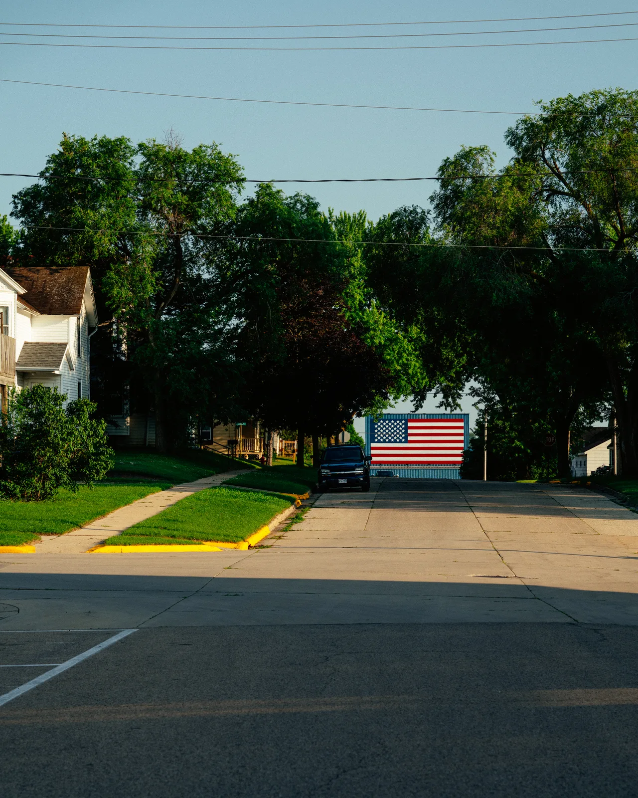 An American flag mural at the end of a tree-lined residential street