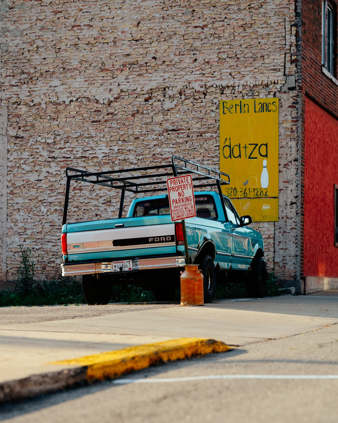 A turquoise Ford pickup parked beneath a Berlin Lanes sign