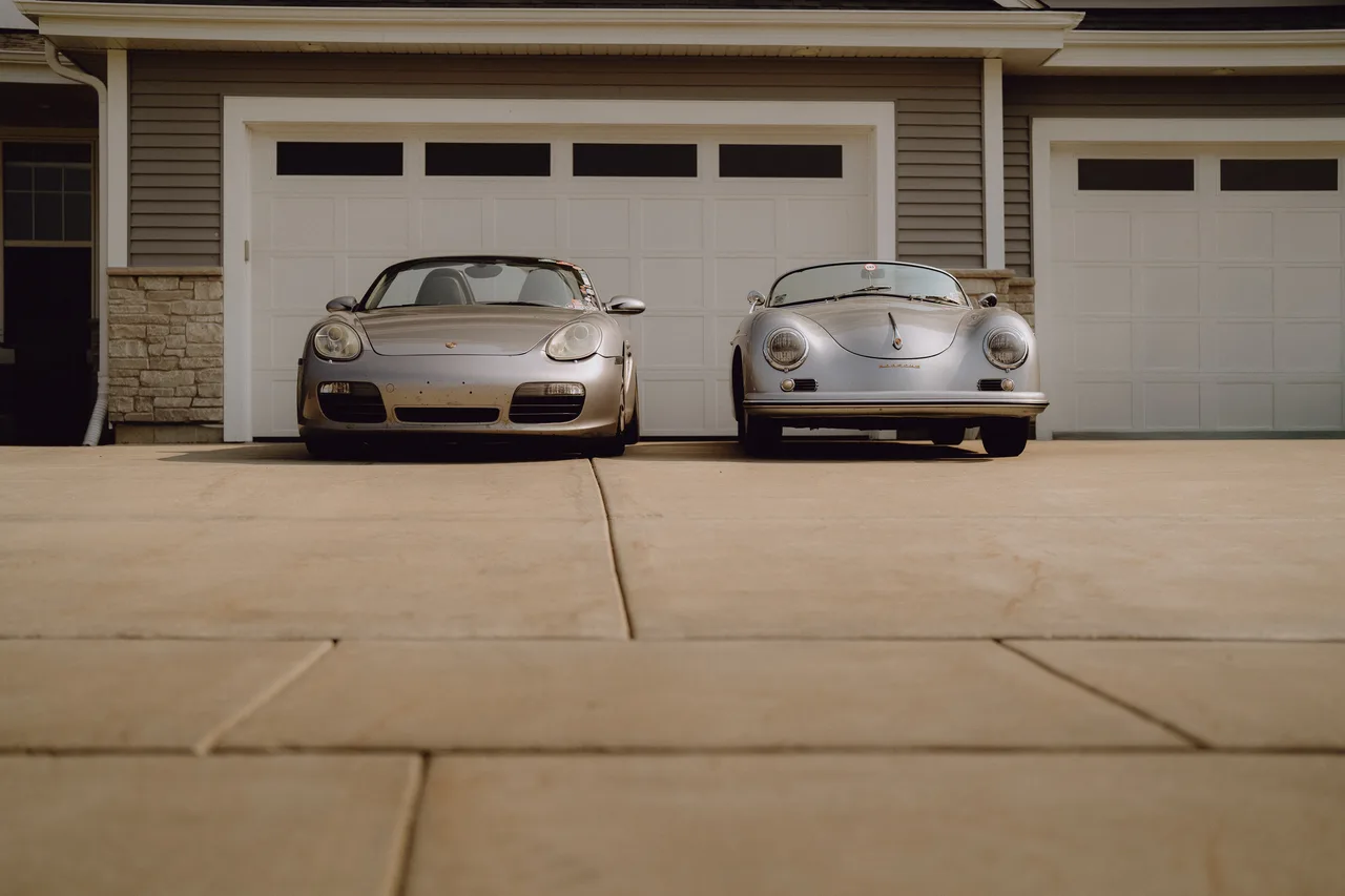 Curt Cromwell’s 1956 Porsche Speedster parked beside a modern Porsche outside a garage