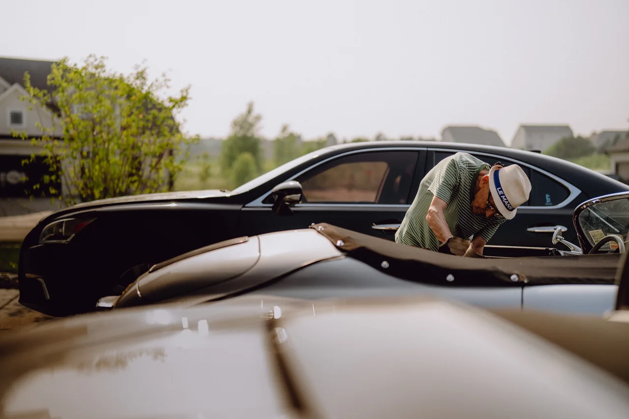 Curt Cromwell leaning into his silver 1956 Porsche Speedster