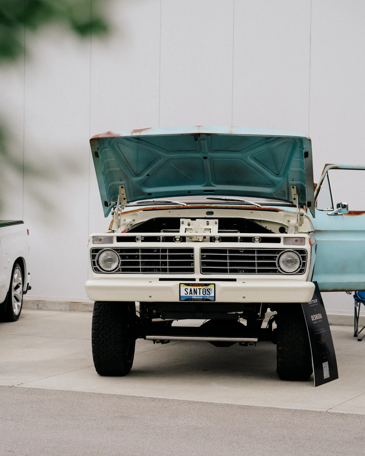 A vintage turquoise-and-white Ford pickup displayed with its hood open