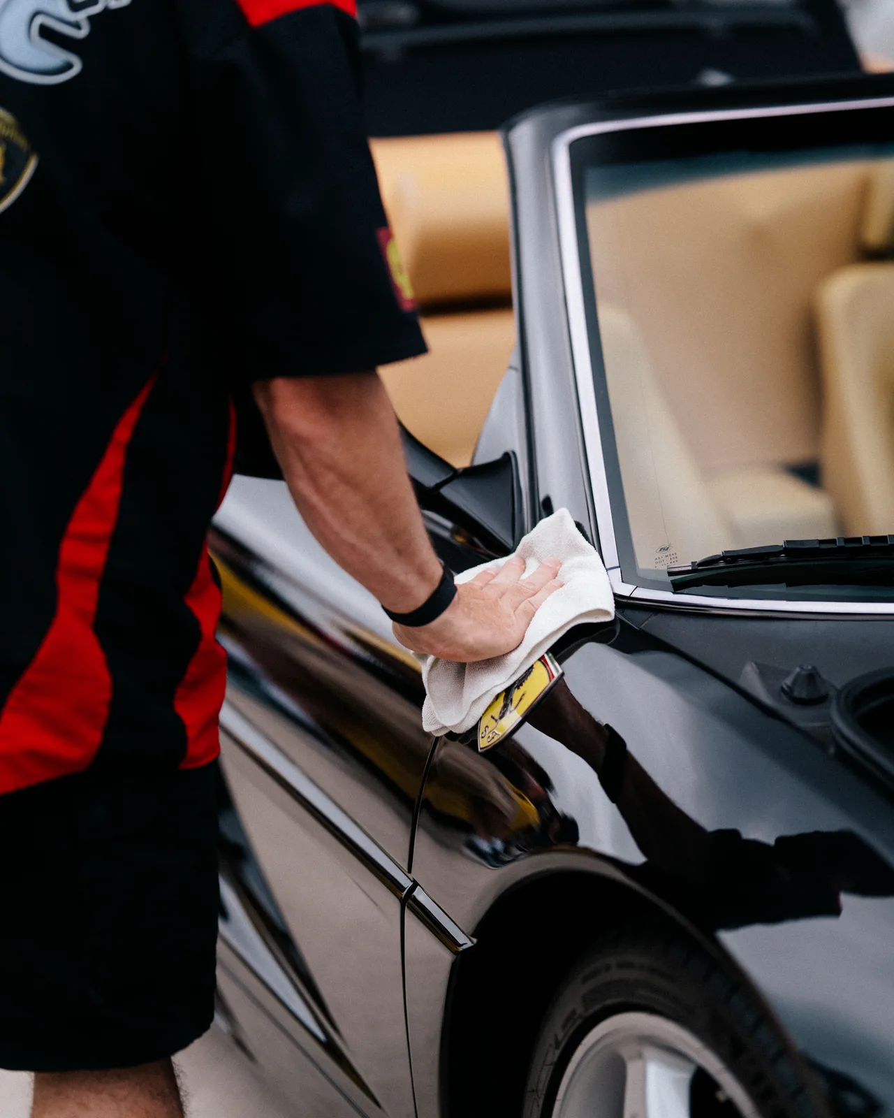 An attendee stepping out of a black sports car at Cars and Coffee