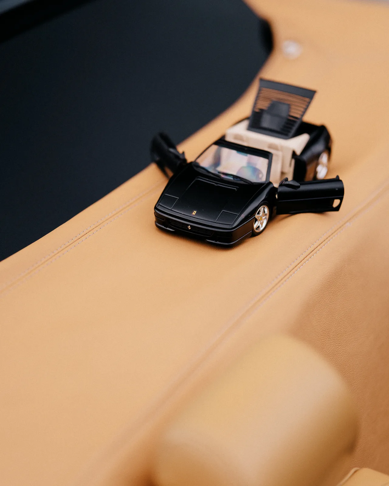A miniature black sports car resting on a tan leather seat