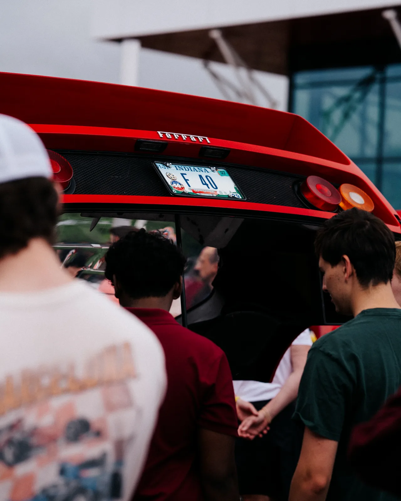 A crowd gathered around the rear of a red Ferrari