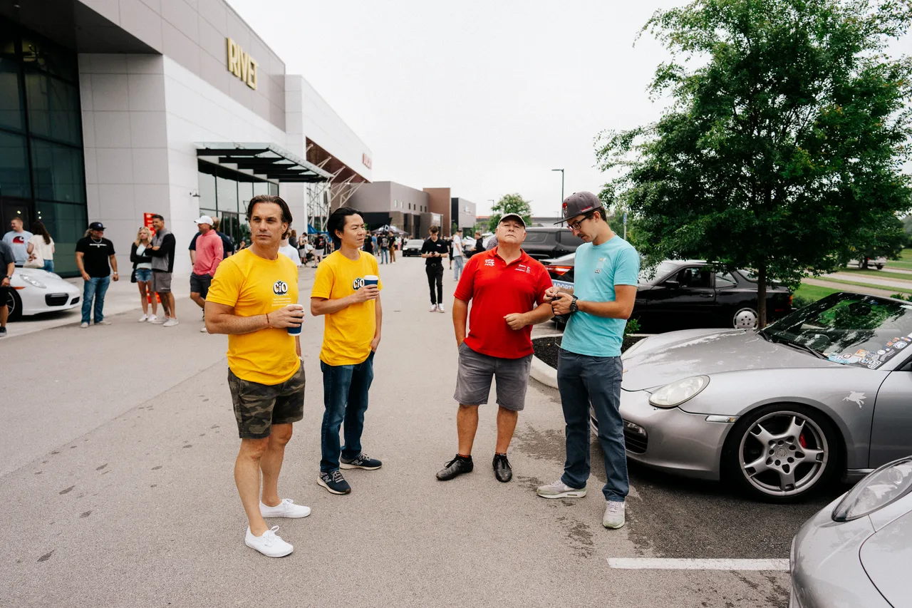 Checkeditout crew and guests gathered among parked sports cars in Zionsville